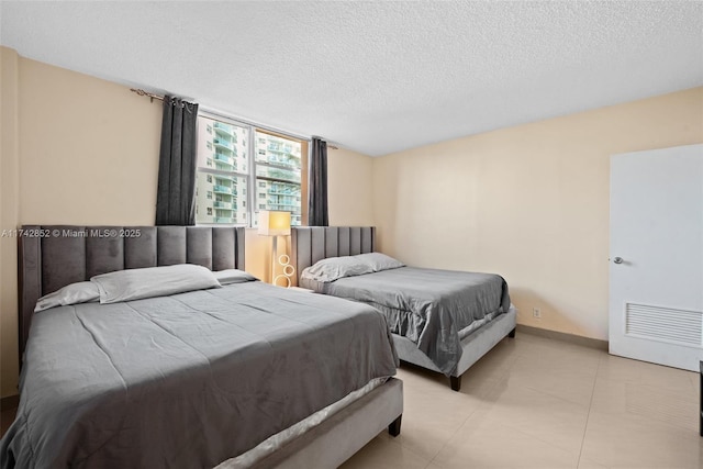 bedroom with light tile patterned floors, baseboards, and a textured ceiling