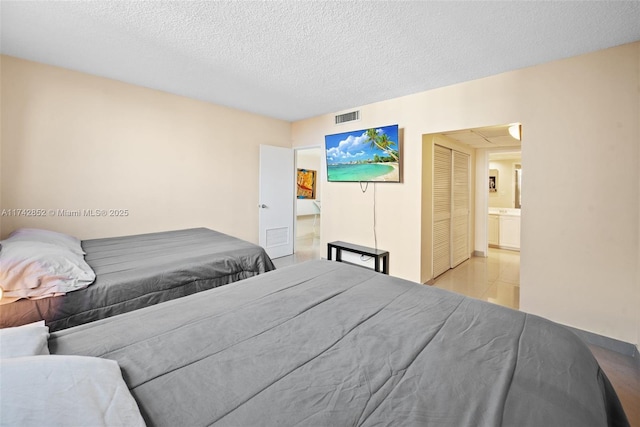 bedroom with a closet, visible vents, a textured ceiling, and light tile patterned flooring