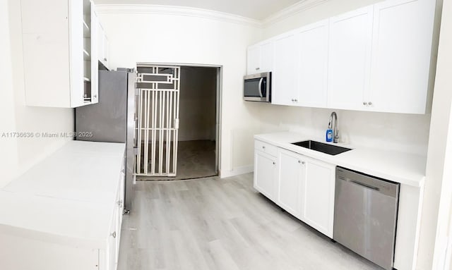 kitchen featuring white cabinetry, stainless steel appliances, crown molding, and sink