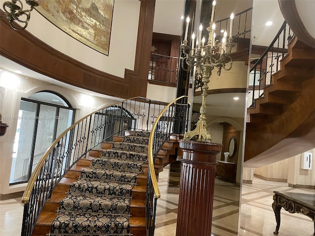 stairway featuring arched walkways, a towering ceiling, and a notable chandelier