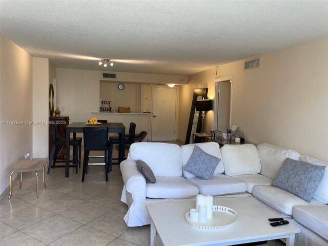 living room with visible vents, a textured ceiling, and light tile patterned flooring