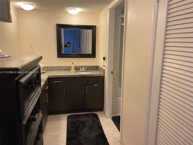 full bath featuring tile patterned flooring, a closet, a textured ceiling, and vanity