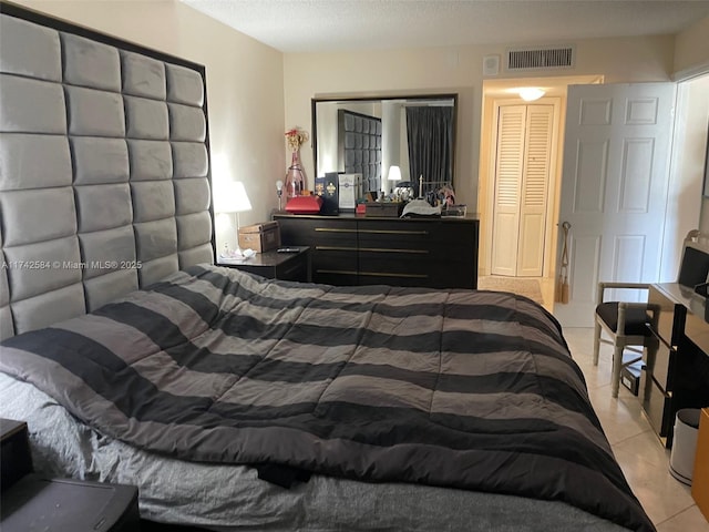 bedroom with visible vents, a textured ceiling, and light tile patterned floors