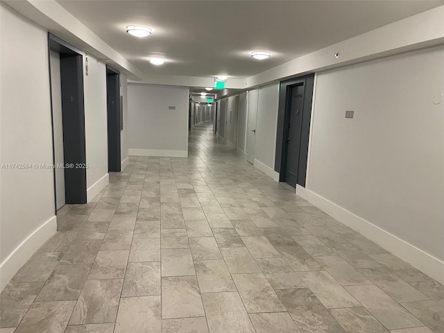 hallway with elevator and baseboards