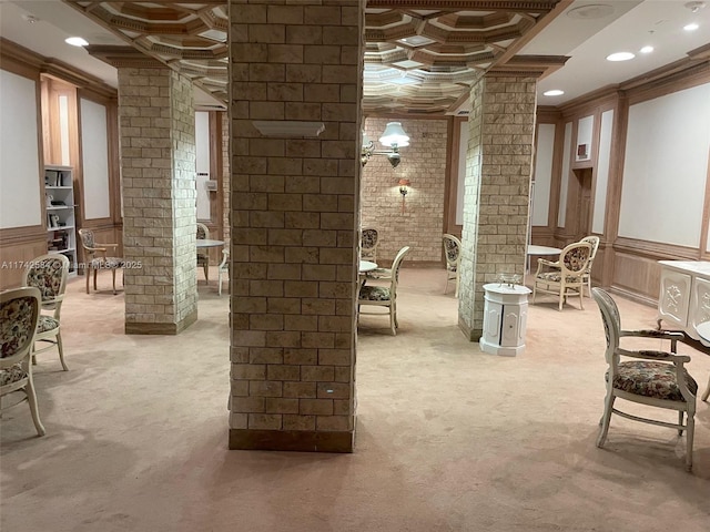 interior space featuring light carpet, ornate columns, coffered ceiling, and wainscoting