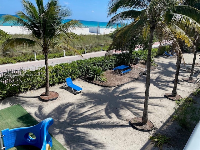 surrounding community featuring a water view, fence, and a view of the beach