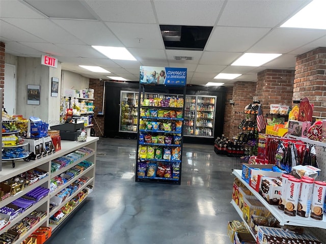 misc room with concrete flooring, a paneled ceiling, visible vents, and brick wall