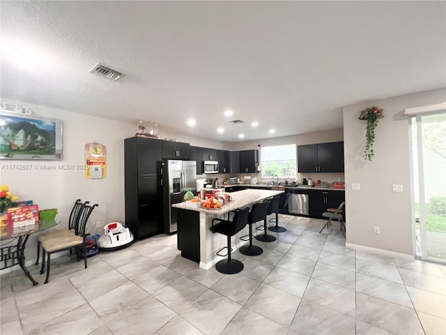 6411 Osprey Landing St, Davie, FL 33314 - kitchen featuring dark cabinetry, appliances with stainless steel finishes, visible vents, and a breakfast bar
