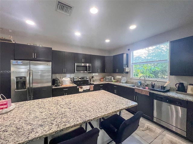 6411 Osprey Landing St, Davie, FL 33314 - kitchen with light stone counters, stainless steel appliances, a kitchen bar, and visible vents