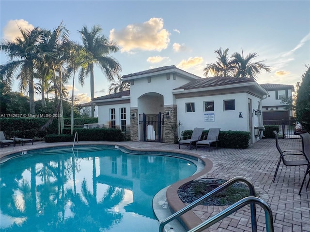 6411 Osprey Landing St, Davie, FL 33314 - pool at dusk with a community pool, fence, and a patio