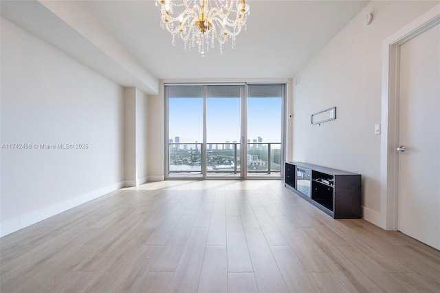 unfurnished living room featuring baseboards, floor to ceiling windows, and light wood finished floors