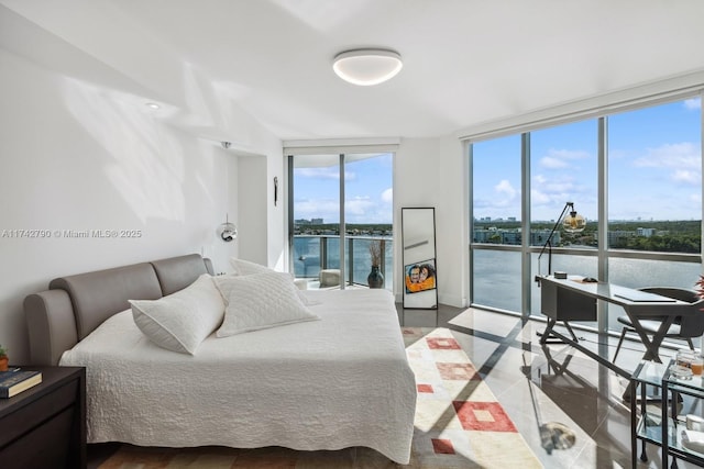 bedroom with floor to ceiling windows, a water view, and access to exterior