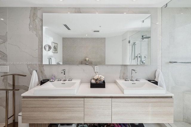 bathroom featuring vanity, a shower with door, tile walls, and backsplash