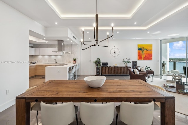 dining area featuring floor to ceiling windows, a water view, and a tray ceiling