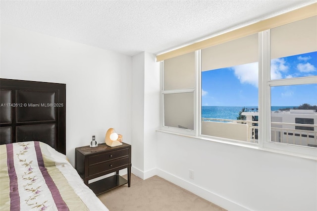 carpeted bedroom with a beach view, a textured ceiling, and a water view