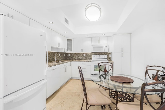 kitchen with tasteful backsplash, sink, white cabinets, a raised ceiling, and white appliances