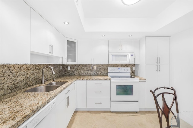 kitchen with white appliances, a raised ceiling, sink, and white cabinets