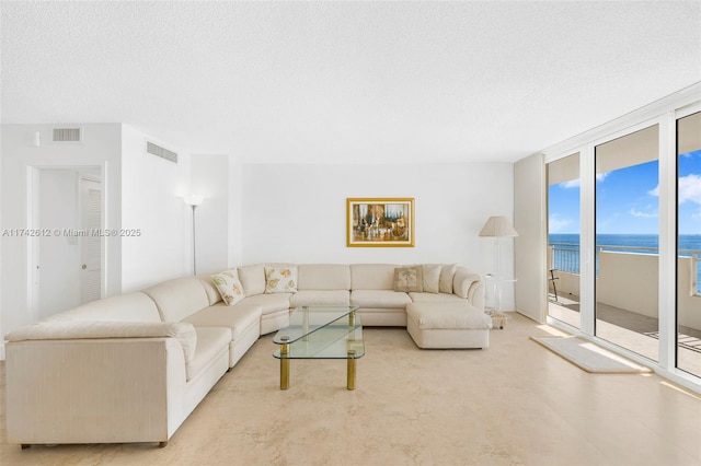 living room featuring a water view, a textured ceiling, and a wall of windows