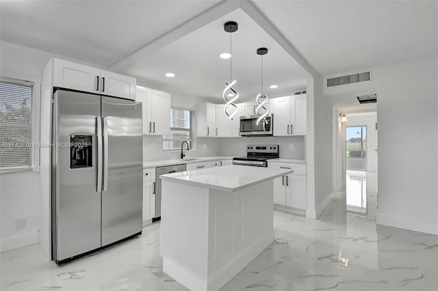 kitchen featuring decorative light fixtures, white cabinetry, sink, a center island, and stainless steel appliances