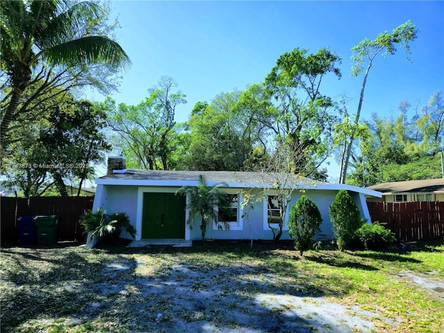 view of front of home featuring a chimney, fence, and stucco siding