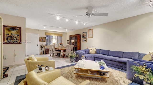 living room featuring a ceiling fan, a textured ceiling, and light tile patterned floors