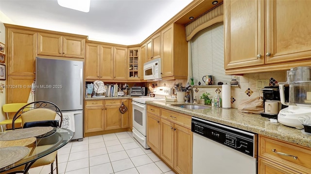 kitchen featuring light tile patterned floors, light stone counters, white appliances, a sink, and decorative backsplash