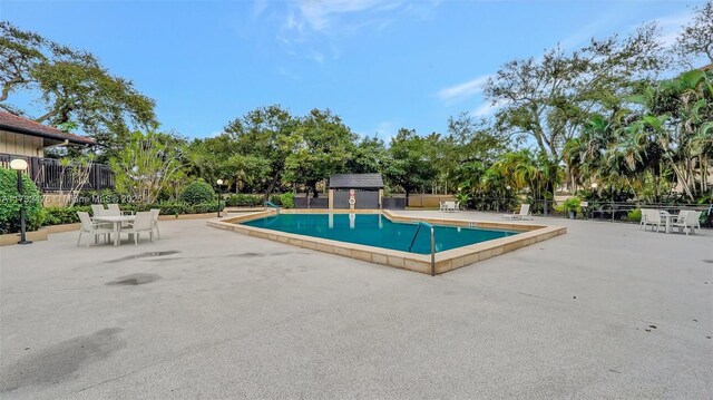 481 Ives Dairy Rd Unit 105-4, Miami, FL 33179 - community pool with a patio, fence, an outdoor structure, and a storage unit