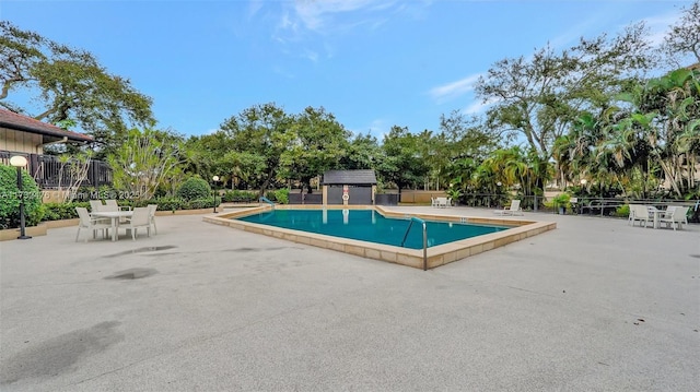 view of swimming pool featuring a patio area and fence