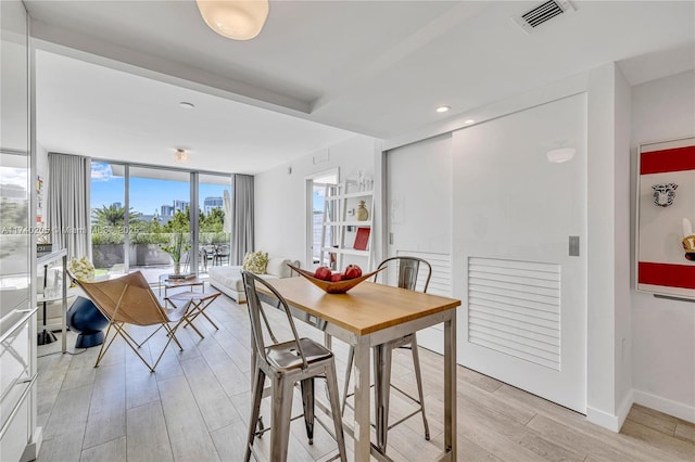 dining area featuring a wall of windows and light hardwood / wood-style floors