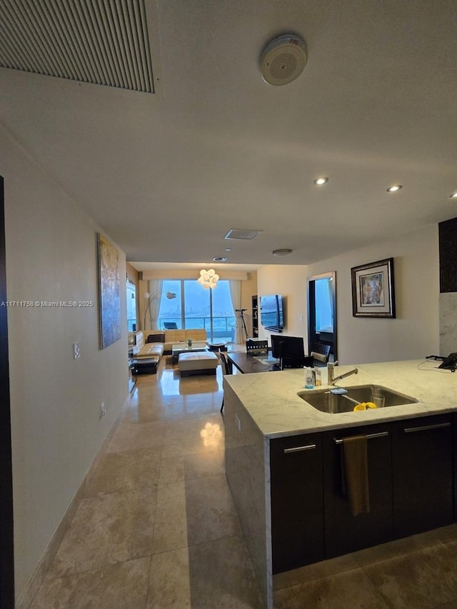 kitchen with light stone counters, light tile patterned flooring, and sink