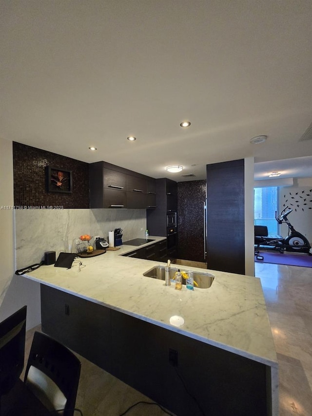 kitchen with a breakfast bar, kitchen peninsula, sink, and decorative backsplash