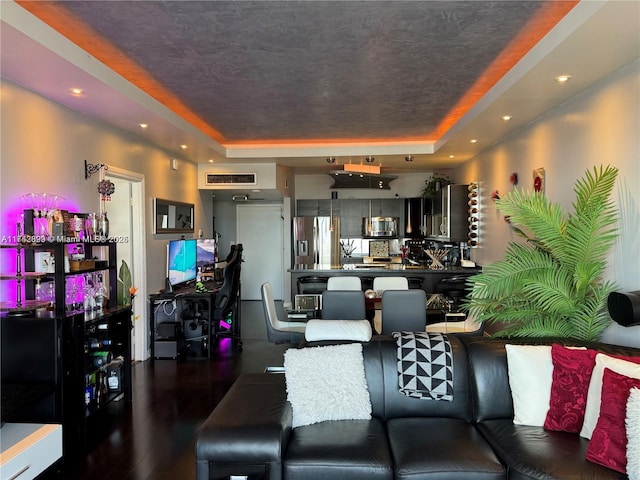 living room featuring a textured ceiling, dark hardwood / wood-style flooring, and a tray ceiling