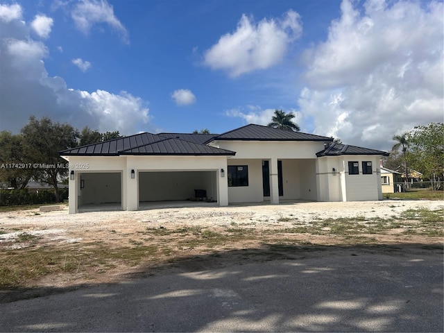 view of front facade with metal roof, a standing seam roof, an attached garage, and stucco siding