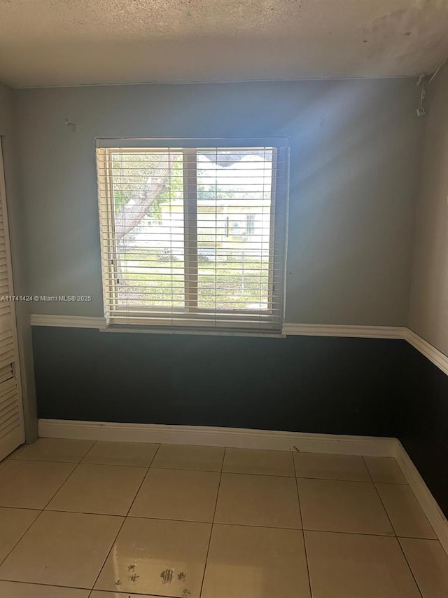 tiled spare room featuring a textured ceiling