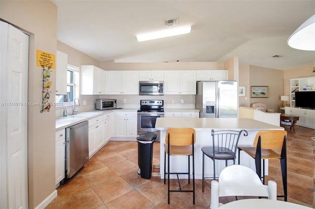 12239 SW 140th St, Miami, FL 33186 - kitchen with stainless steel appliances, a sink, a breakfast bar, lofted ceiling, and white cabinets