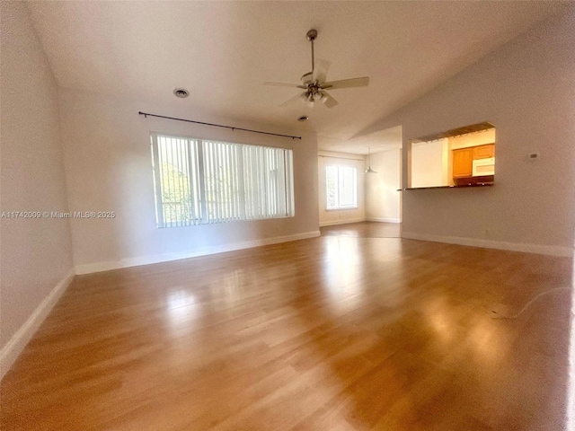 unfurnished room featuring lofted ceiling, light wood-style flooring, baseboards, and ceiling fan