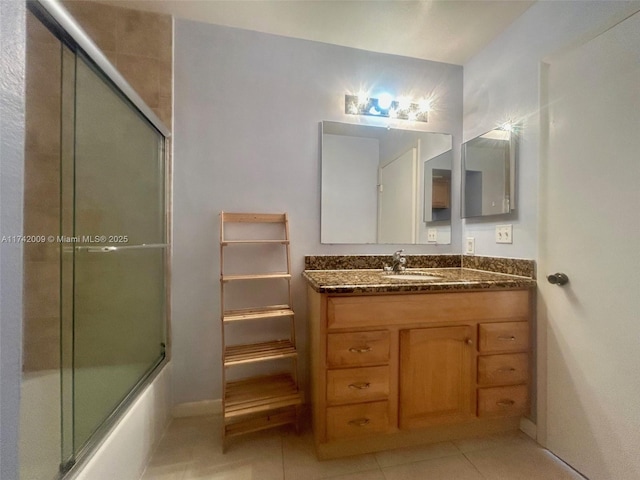 bathroom with combined bath / shower with glass door, vanity, and tile patterned floors