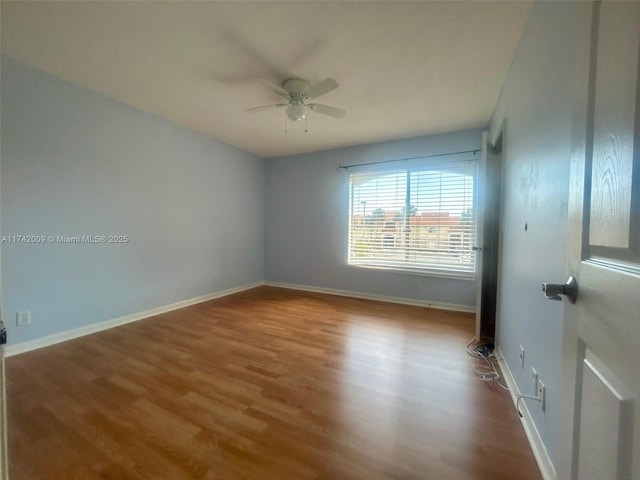 unfurnished room with a ceiling fan, baseboards, and wood finished floors