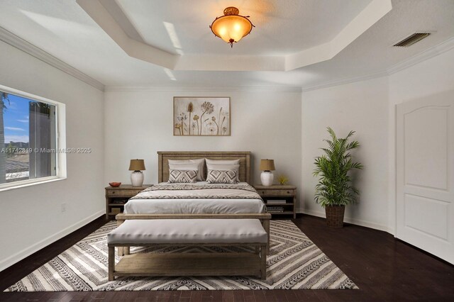 bedroom with dark hardwood / wood-style floors and a raised ceiling