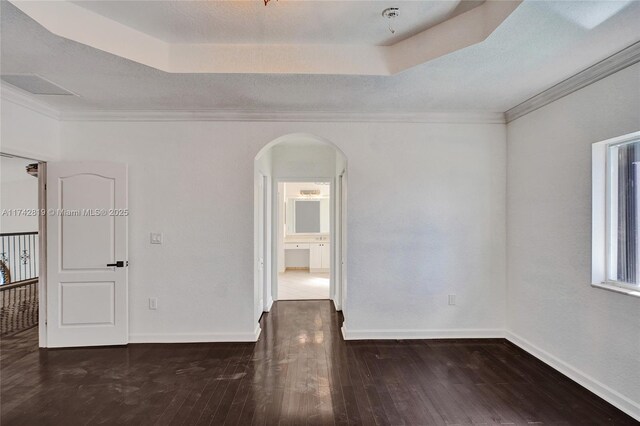 empty room featuring a raised ceiling, ornamental molding, and dark hardwood / wood-style floors