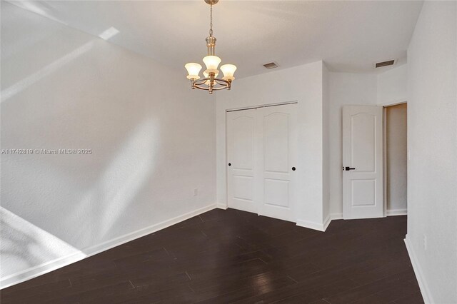 spare room featuring dark hardwood / wood-style floors and a chandelier