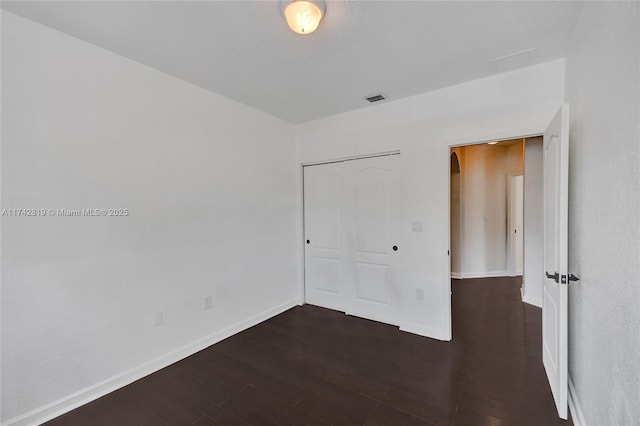 unfurnished bedroom featuring dark hardwood / wood-style flooring and a closet