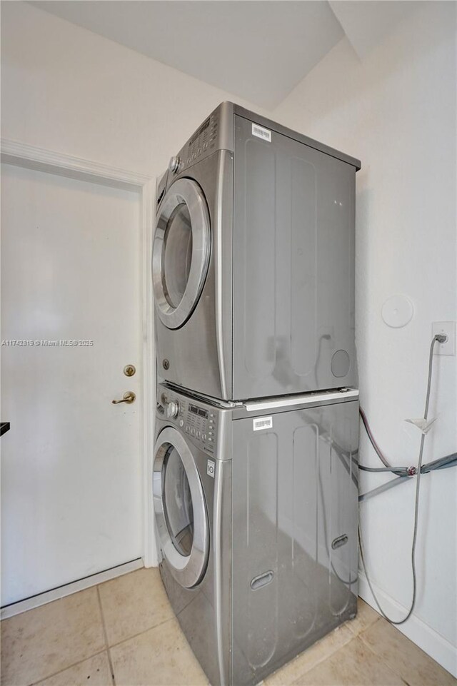 clothes washing area featuring light tile patterned flooring and stacked washer and dryer