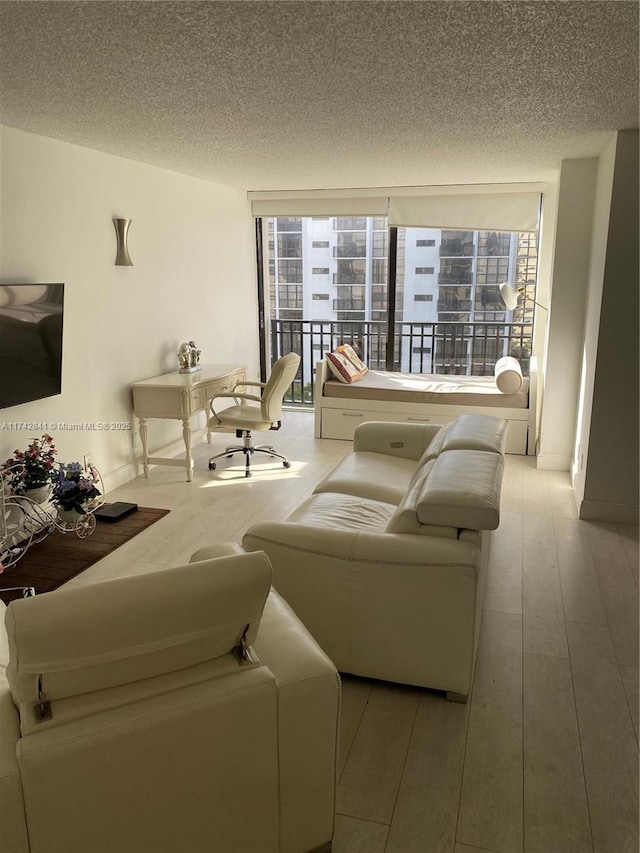 living room featuring floor to ceiling windows, a textured ceiling, and light hardwood / wood-style flooring