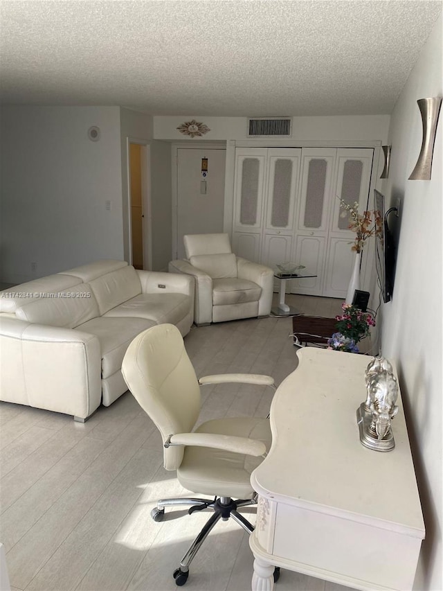 living room featuring light hardwood / wood-style floors and a textured ceiling