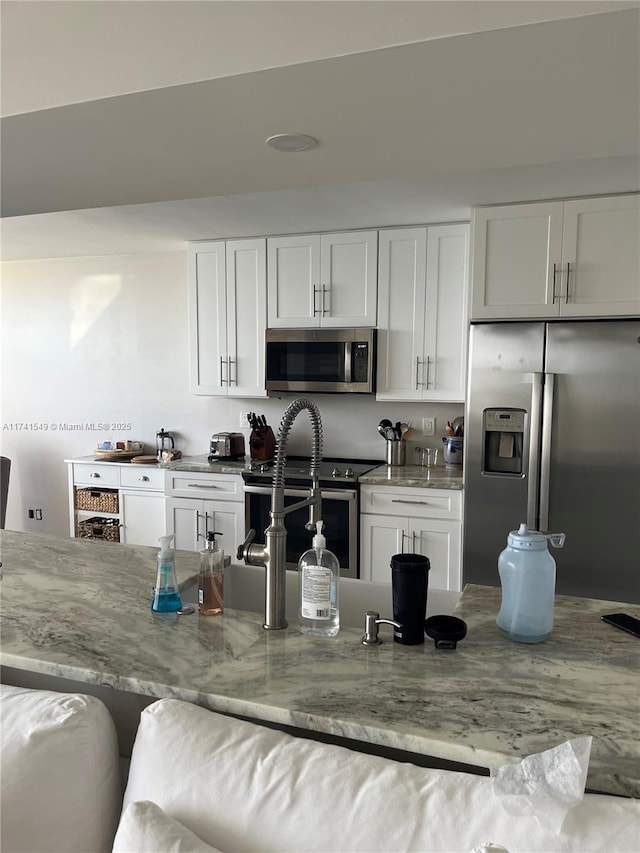 kitchen with white cabinetry, light stone countertops, and stainless steel appliances