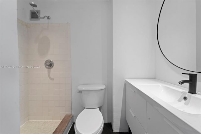 bathroom featuring vanity, tiled shower, and toilet