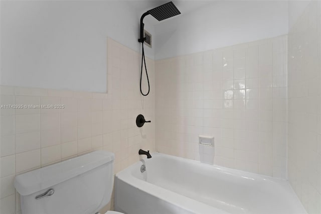 bathroom with tile walls, tiled shower / bath, and toilet