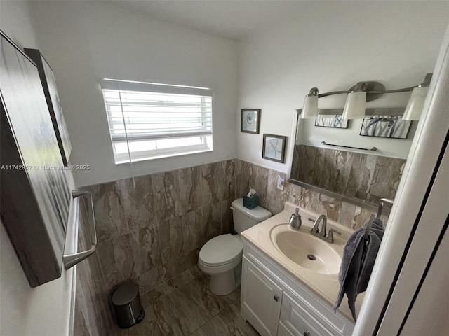 bathroom with vanity, toilet, and tile walls