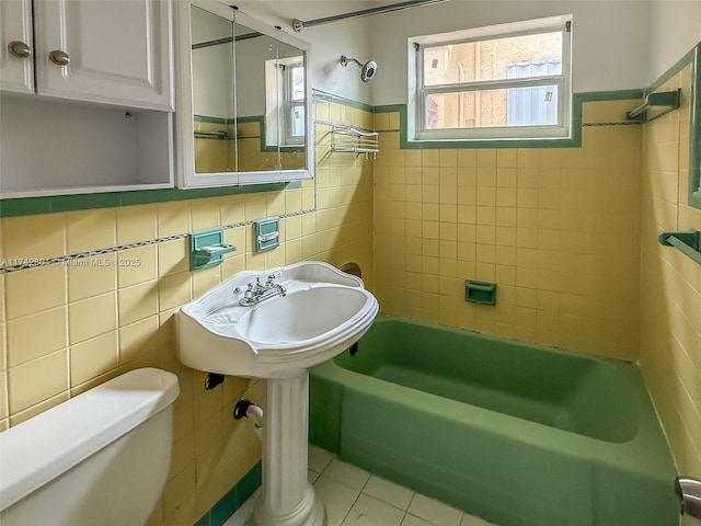 full bathroom with sink, tile patterned flooring, tile walls, toilet, and tiled shower / bath